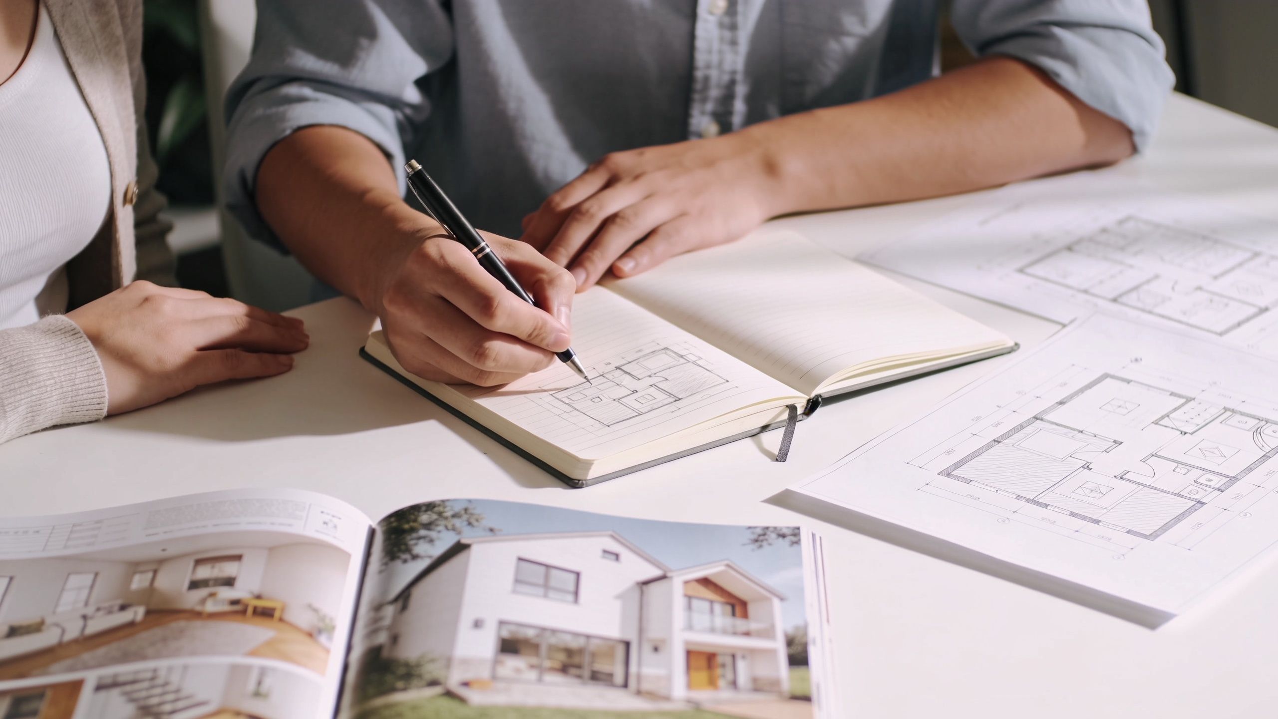 En arkitekt og en kunde gennemgår plantegninger og designs til en omfattende ombygning af et hus